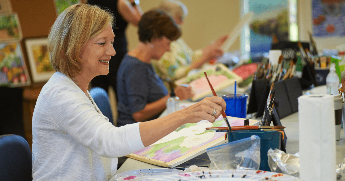 Smiling woman painting during an art class.