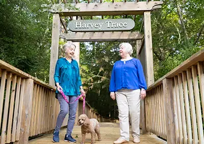 two women on bridge walking dog and talking