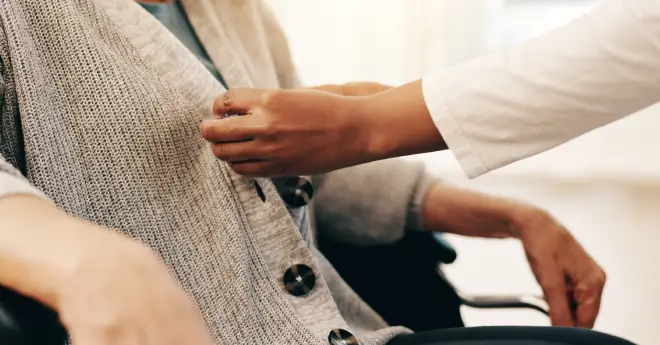 a resident getting help buttoning up their sweater