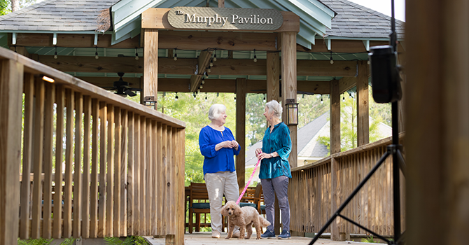 two women on bridge walking dog and talking